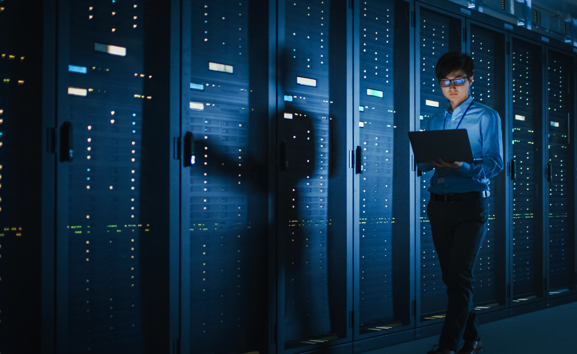 Man holding a laptop in a computer room